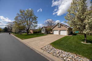 View of front of home featuring concrete driveway, a front yard, and a garage