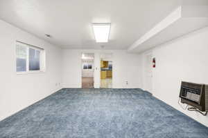 Interior space featuring dark carpet, baseboards, and heating unit