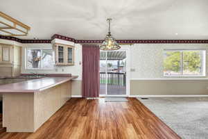 Kitchen with light wood-style floors, glass insert cabinets, plenty of natural light, and a sink