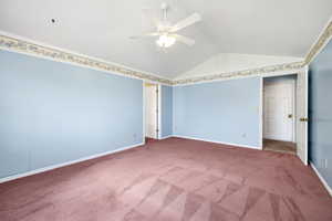 Unfurnished bedroom with lofted ceiling, baseboards, a ceiling fan, and carpet flooring