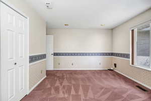 Spare room with carpet floors, wallpapered walls, visible vents, and baseboards