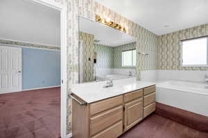 Bathroom with a bath, visible vents, vanity, and wallpapered walls