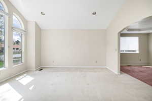 Interior space with arched walkways, a wealth of natural light, baseboards, and light carpet