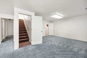 Below grade area with baseboards, carpet floors, and stairway