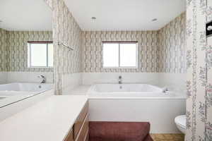 Full bath with wallpapered walls, a bath, toilet, and vanity
