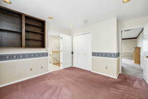 Unfurnished bedroom featuring wallpapered walls, a closet, a wainscoted wall, carpet flooring, and visible vents