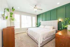 Primary bedroom featuring a decorative wall, a ceiling fan and recessed lighting