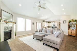 Living room with baseboards, recessed lighting, lofted ceiling, a ceiling fan, and a fireplace