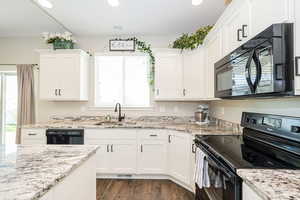 Kitchen featuring a sink, black appliances, a healthy amount of sunlight, white cabinetry, and recessed lighting