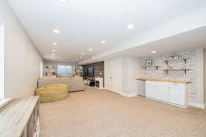 Interior space featuring fridge in dry-bar, a fireplace, light colored carpet, and recessed lighting