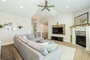 Living area featuring recessed lighting, lofted ceiling, a premium fireplace, baseboards, and ceiling fan