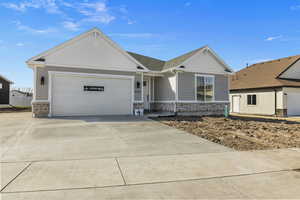Ranch-style home with concrete driveway, roof with shingles, stone siding, and a garage