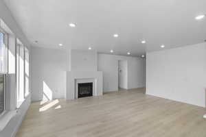 Unfurnished living room featuring light wood-style flooring, a glass covered fireplace, and recessed lighting