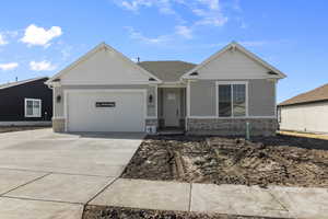 View of front of home with an attached garage, driveway, and stone siding