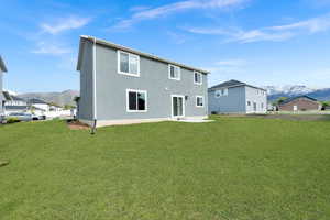 Back of property with a yard, a mountain view, and stucco siding