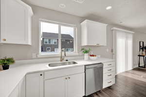 Kitchen featuring stainless steel dishwasher, white cabinetry, quartz countertops and brass details!