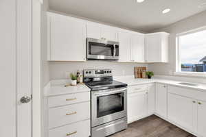 Kitchen featuring quartz countertops, white cabinets, appliances with stainless steel finishes, and recessed lighting