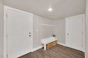 Mudroom with recessed lighting, wood finished floors, built in bench.