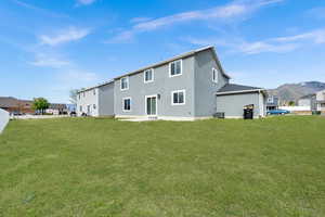 Back of house with a lawn, central AC unit, and stucco siding