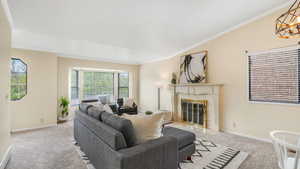 Living room with a tiled fireplace, light colored carpet, and crown molding