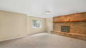 Unfurnished living room with a fireplace, carpet floors, and baseboards