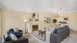 Carpeted living room featuring vaulted ceiling, visible vents, ornamental molding, baseboards, and a notable chandelier