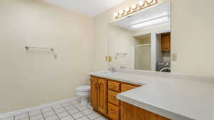 Full bathroom with a shower stall, vanity, washer / dryer, toilet, and tile patterned flooring