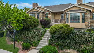 View of front of house with stairway, a chimney, stone siding, and stucco siding