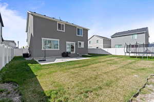Rear view of property featuring a patio area, a fenced backyard with 2 gates, and a trampoline