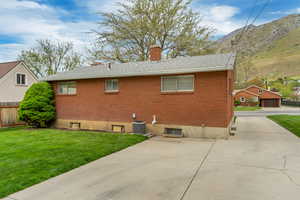 Back of house with a chimney, central AC unit, fence, a yard, and a mountain view