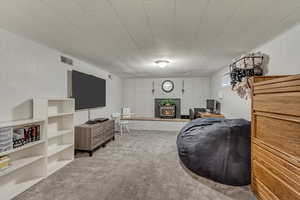 Carpeted living area with visible vents and a wood stove