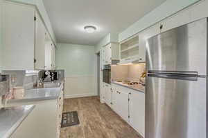 Kitchen with oven, a sink, freestanding refrigerator, wainscoting, and white electric stovetop