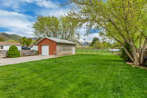 View of yard featuring fence, concrete driveway, an outbuilding, a detached garage, and a mountain view