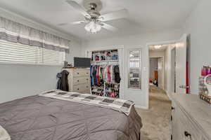Bedroom with a ceiling fan, a closet, and light colored carpet