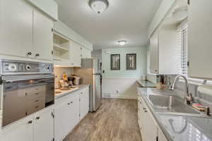Kitchen featuring light wood finished floors, a wainscoted wall, oven, visible vents, and a sink