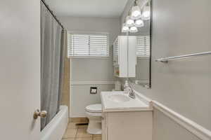 Bathroom with shower / bath combo, vanity, tile patterned flooring, and toilet