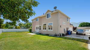 Rear view of property with stucco siding, central air condition unit, a lawn, and fence
