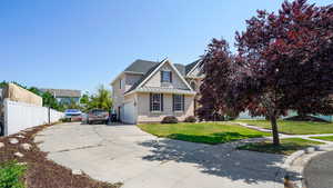 Traditional-style house featuring stucco siding, a front lawn, driveway, and fence