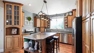 Kitchen featuring stainless steel appliances, stainless steel counters, a sink, open shelves, and a breakfast bar