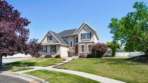 View of front of property featuring stone siding, a front yard, stucco siding, and fence