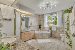 Full bath featuring visible vents, a notable chandelier, tile patterned flooring, a garden tub, and vanity
