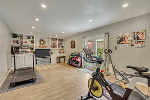Workout area with light wood finished floors, baseboards, and recessed lighting