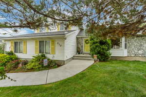 View of front of home featuring stone siding and a front yard