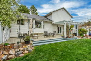 Back of property with a pergola, a yard, roof with shingles, and a patio