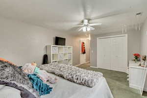 Carpeted bedroom with ceiling fan, baseboards, and a closet