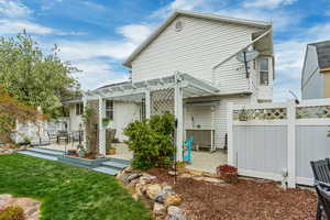 Rear view of property featuring a pergola, a patio area, and fence