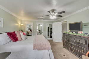 Carpeted bedroom featuring attic access, ceiling fan, crown molding, and visible vents