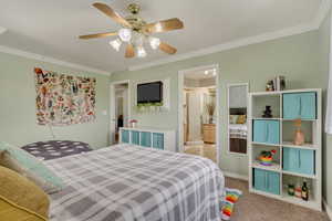 Carpeted bedroom featuring ensuite bath, crown molding, and a ceiling fan