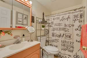 Bathroom featuring a shower with shower curtain, visible vents, toilet, and vanity