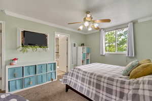 Bedroom featuring a ceiling fan, crown molding, carpet flooring, and ensuite bathroom